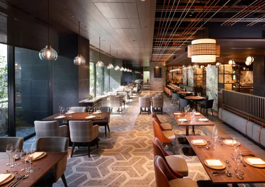 Indoor, hotel dining area with beige chairs and long wooden tables