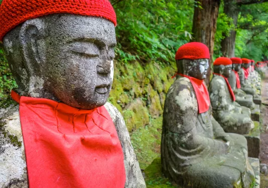 Row of stone statues with knitted hats and red chest coverings