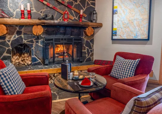 Lounge with cushioned red chairs in front of a stone fireplace