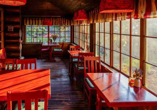 Cabin restaurant with red tables and chairs, with large windows along the walls