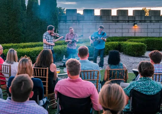 Group of people sitting and watching a small band play outdoors