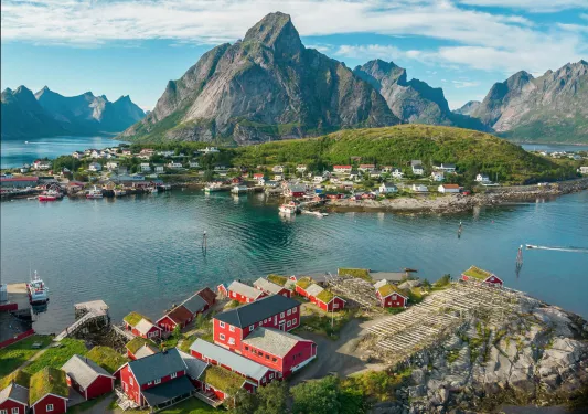 Houses along a river, with mountains in the background