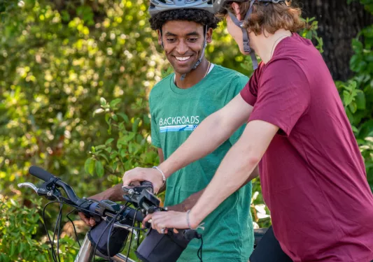 Two teenagers riding bikes while smiling