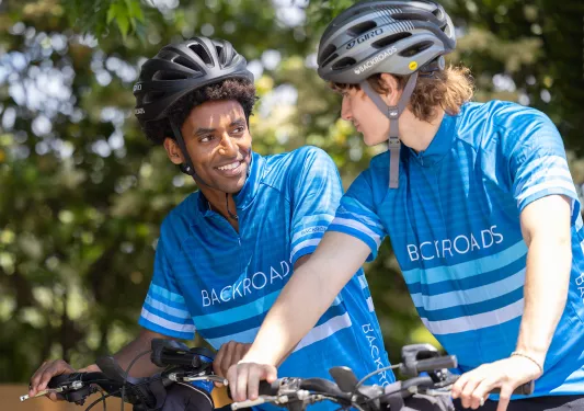 Two men wearing Backroads jerseys, riding on their bicycles