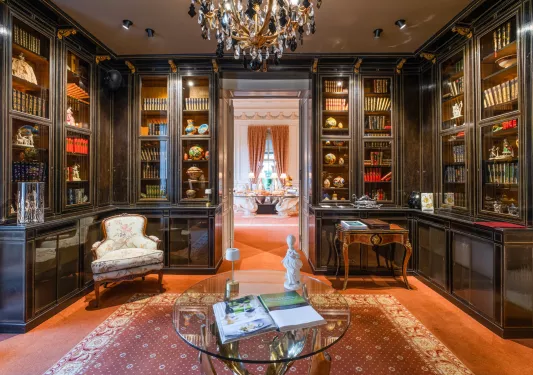 Library with large, wooden and marble shelves and cushioned chairs