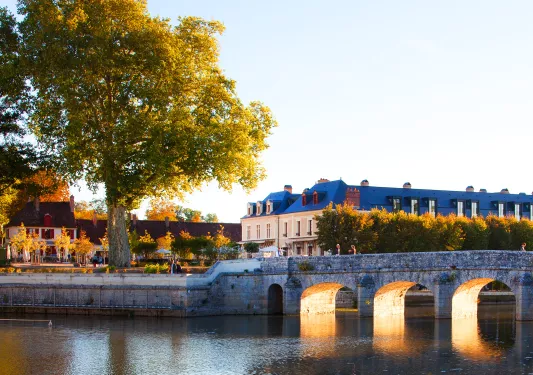 Large white and blue building with a stone bridge and river in front