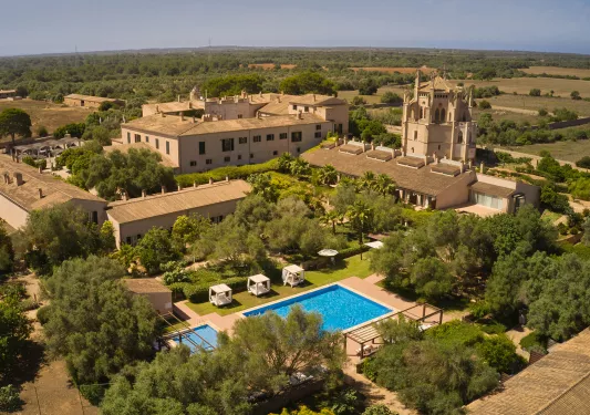 Sky view of brown, hotel buildings with an outdoor pool in the center