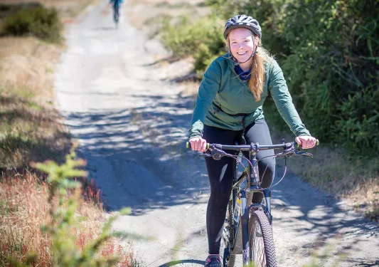 Woman riding a bike on a gravel path