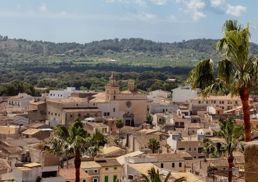 Sky view of town with beige houses and buildings, and a valley in the distance