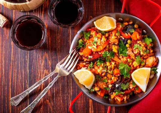 Bowl of paella with cut lemons on the sides