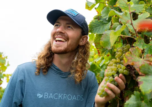 Man smiling while holding a vine of grapes