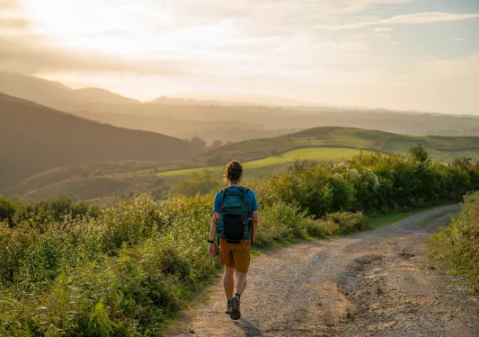 Man descending a dirt trail with the sunset in the background