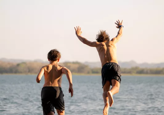 Two teenagers jumping into a large lake