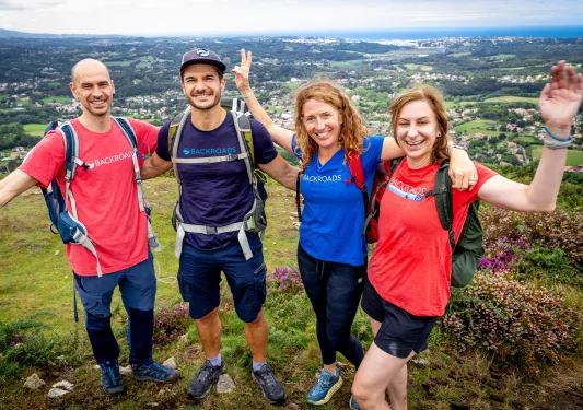 Group of people on top of a hill, smiling with their hands up