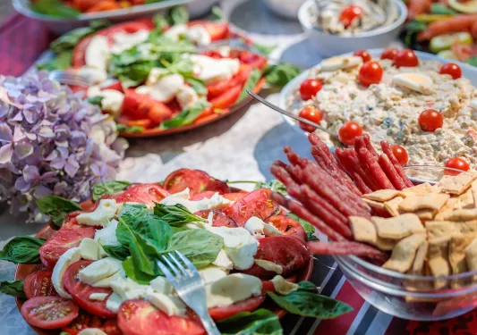 Table with plates of salads and cured meats