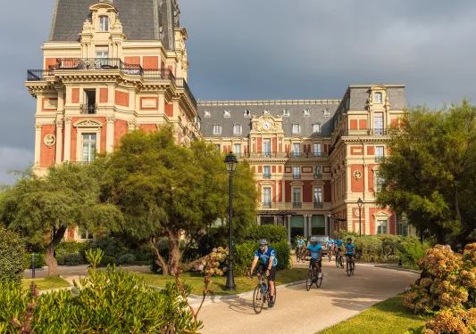 Group of bikers riding in front of a castle-like building