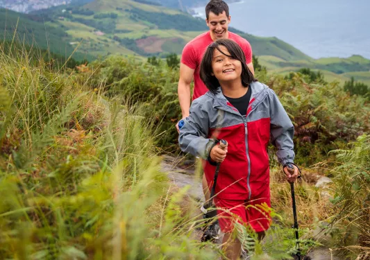 Man and boy hiking on a dirt trail with mountains in the distance