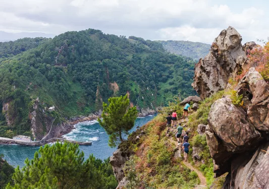 Group of people hiking on a dirt trail on a hill with a river on the ground floor