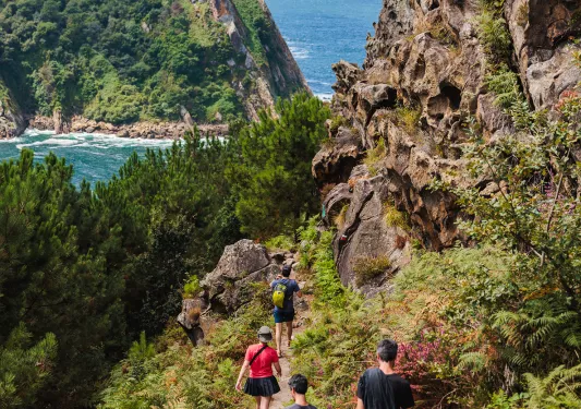 Family hiking on a dirt trail with large cliffs and the ocean in the distance