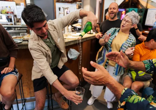 Group of people laughing while a man is pouring a glass of beer