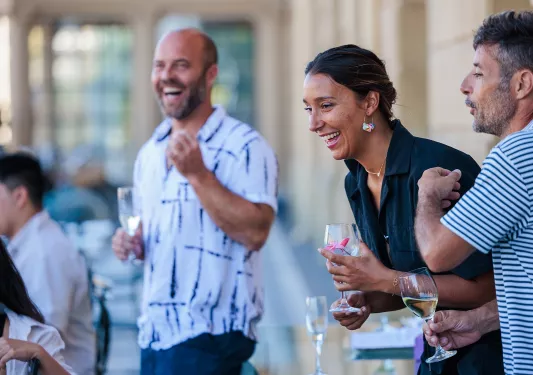 Group of people laughing and smiling while holding glasses of wine