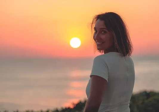 Woman looking back and smiling with the sunset in the background