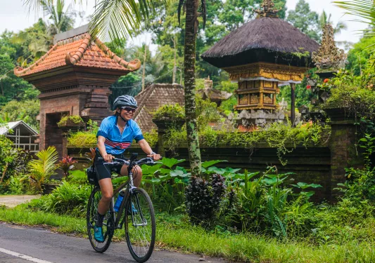 Woman riding a bike with brick buildings and grass in the background
