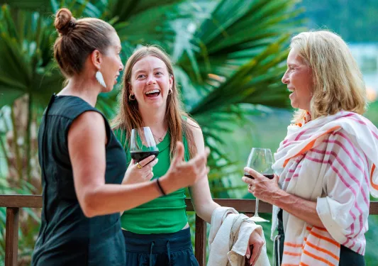 Three women smiling while holding glasses of wine