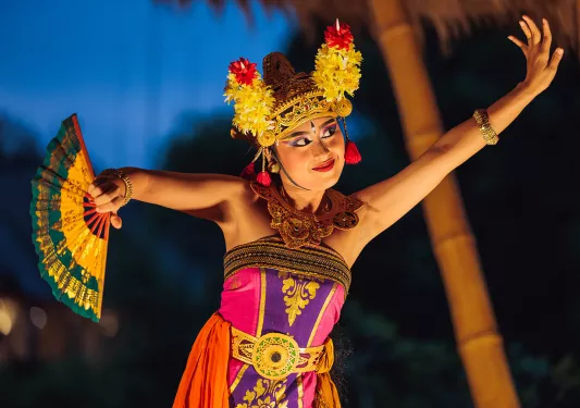 Woman wearing traditional clothing and dancing with a fan in her hand