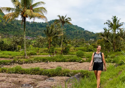 Woman smiling while walking on a field of grass and crops