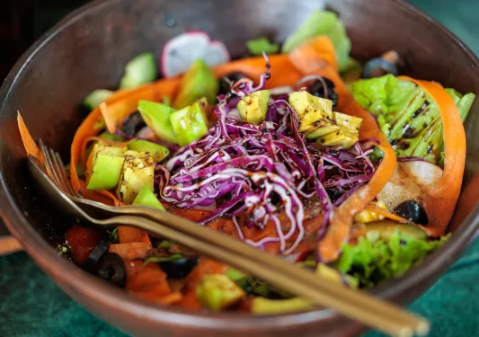Bowl of vegetables and cabbage, with a salad dressing on top