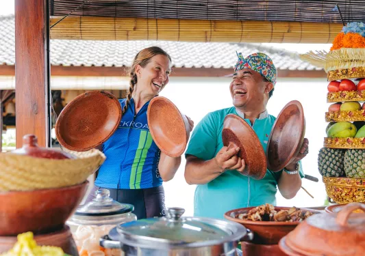 Man and women smiling while holding up lids to clay pots