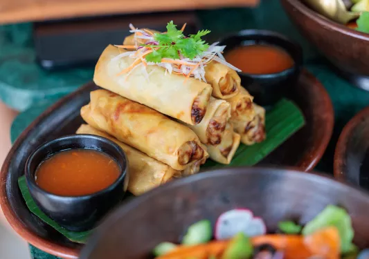 Plate of fried eggrolls with a bowl of red sauce