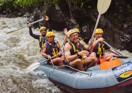 Group of people smiling and paddling in a raft in a river