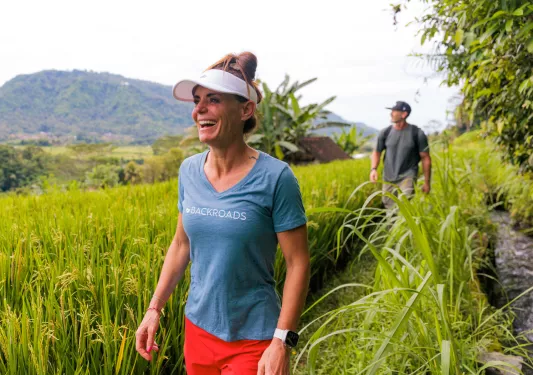 Man and woman smiling while walking through tall weeds