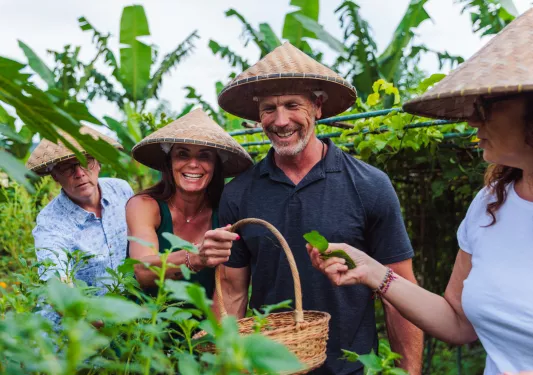 Group of men and women smiling while picking plants
