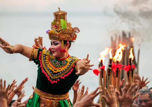 Woman wearing a traditional dress and makeup dancing above a group of people