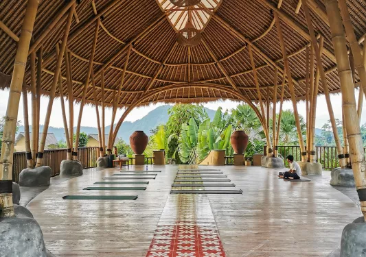 Man sitting in a large open hut, with views of the jungle in the distance