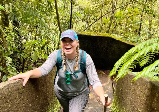 Woman climbing a flight of stone stairs in the middle of a forest