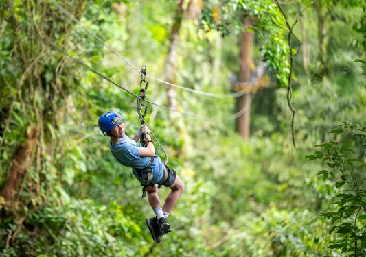 Teen boy laughing while riding a zipline