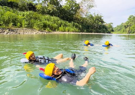 Man and woman smiling while floating in a river