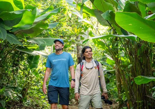 Two men smiling while walking through a jungle