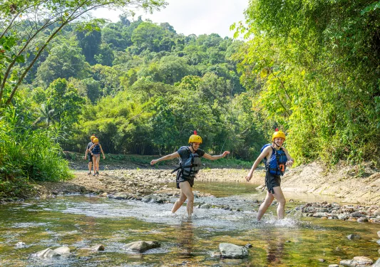 Man and woman wearing life vests, walking through a shallow pond