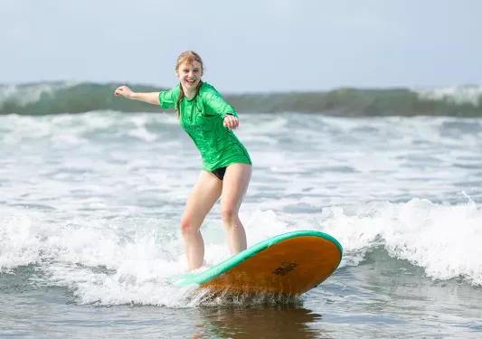 Teenage girl riding a surfboard in the ocean
