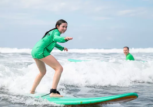 Teen girl riding a green surfboard in the ocean