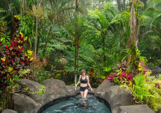 Woman walking into a pool in the middle of a forest