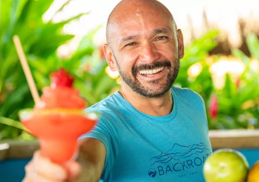 Man smiling while holding out a blended, red drink