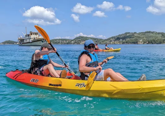 Two boys in a yellow kayak, paddling in the ocean