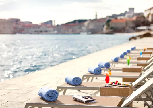 Row of reclining pool chairs on a dock in front of the ocean