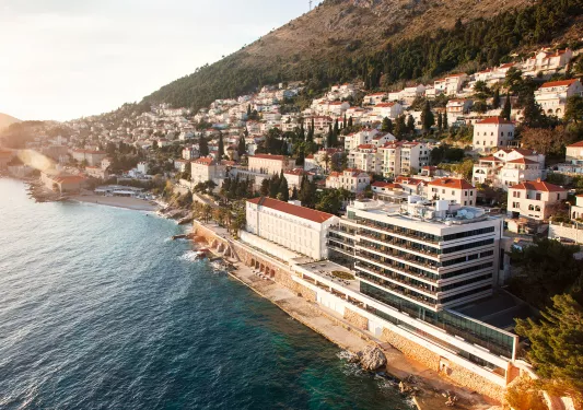 Sky view of a town of white and red buildings with the ocean to the left